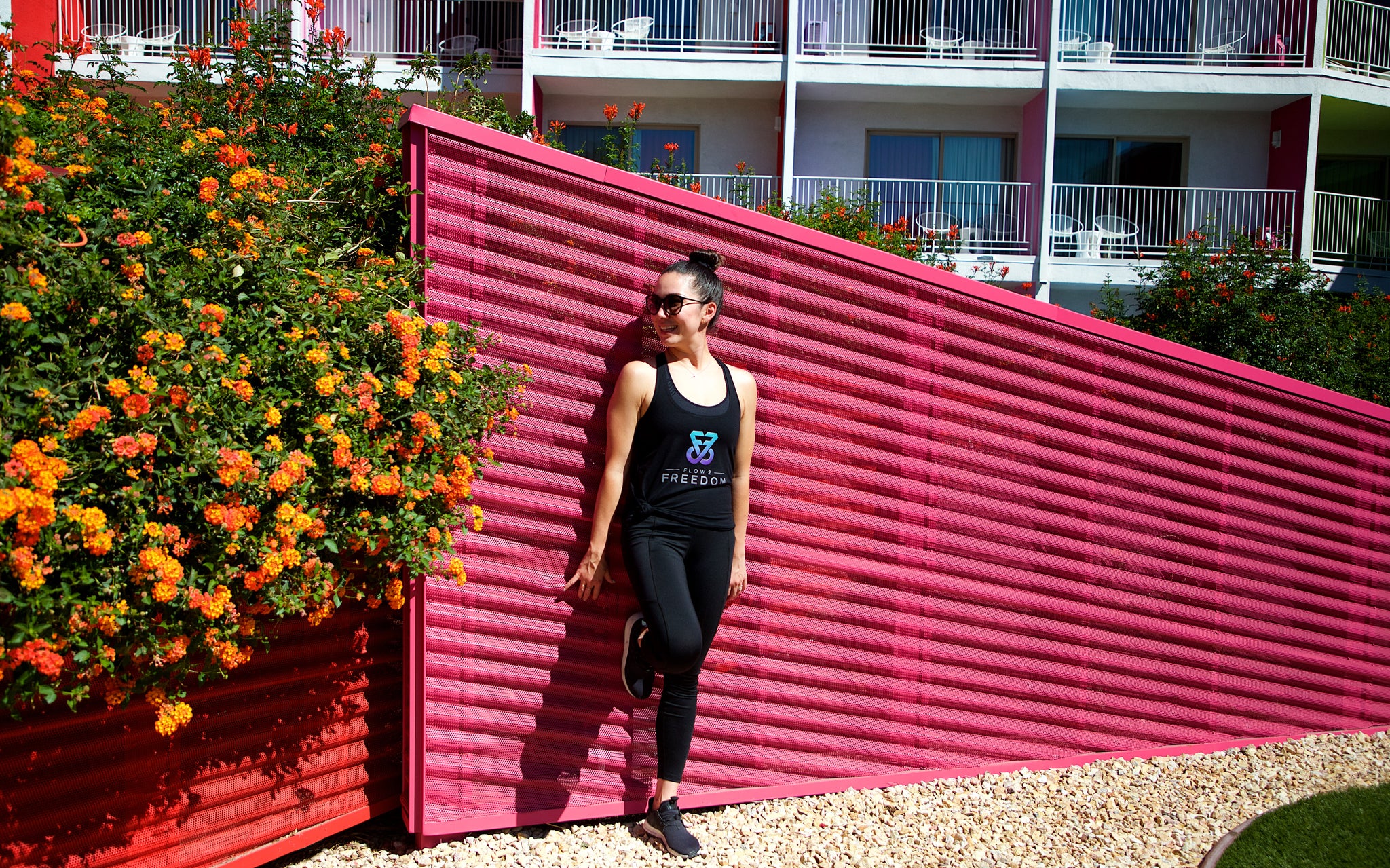 Happy woman standing against pink wall looking at flowers